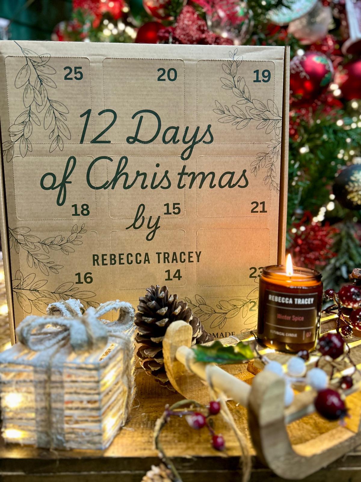 Wooden advent calendar with '12 Days of Christmas' by Rebecca Tracey, surrounded by Christmas decor.