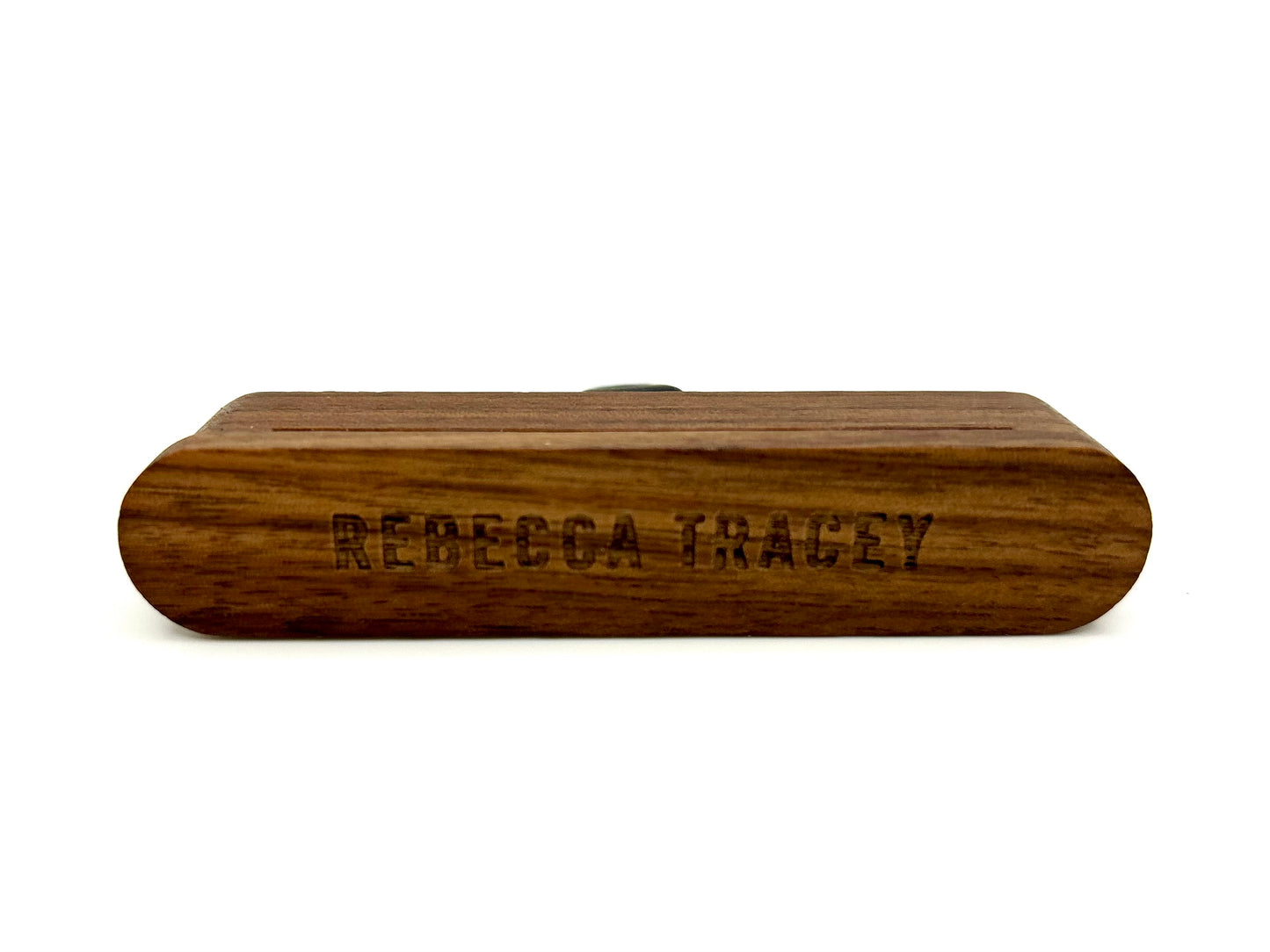A personalized wooden box with rounded ends, featuring the engraved name 'REBECCA TRACEY' on the front, shown against a plain white background.