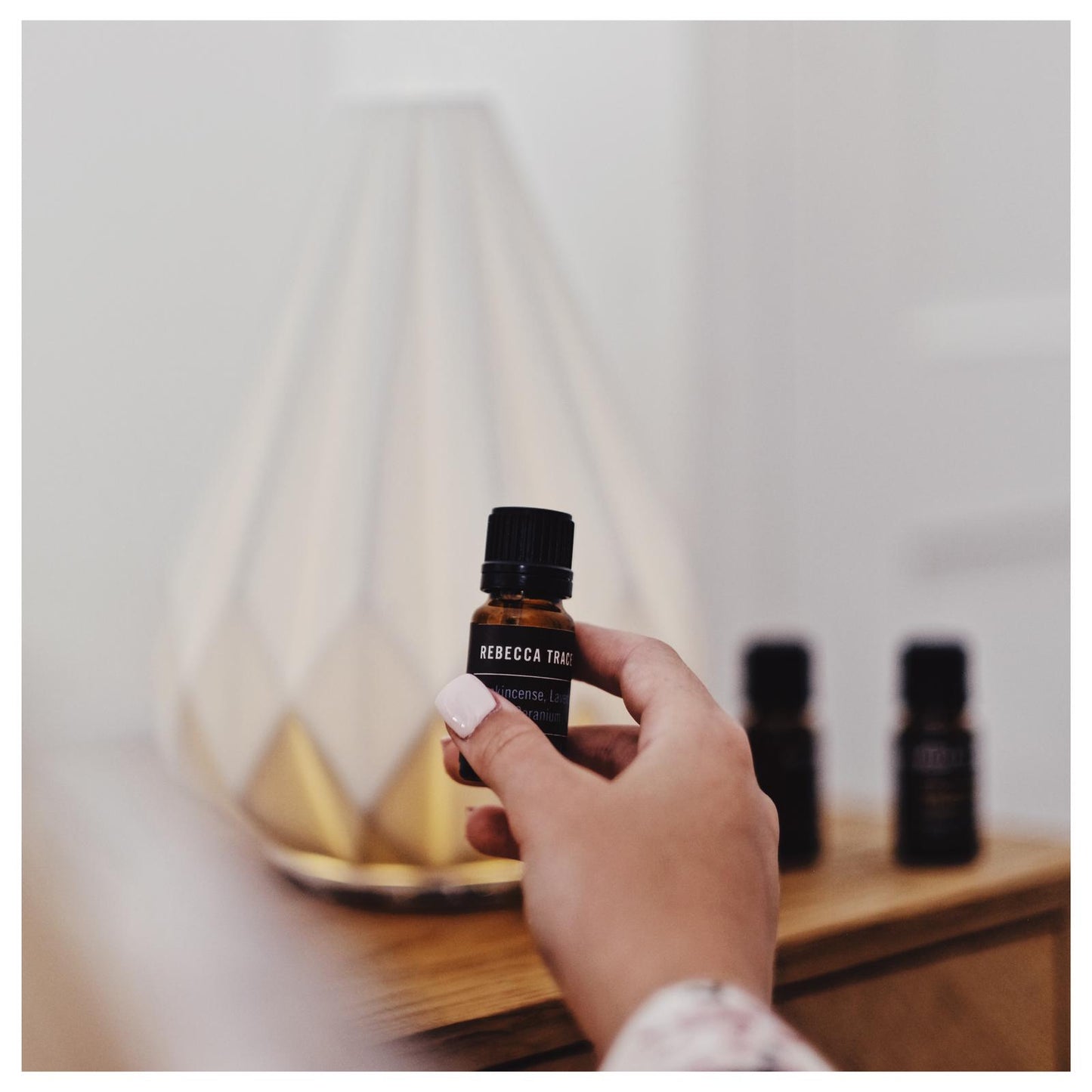 essential oils in a hand with diffuser in the background
