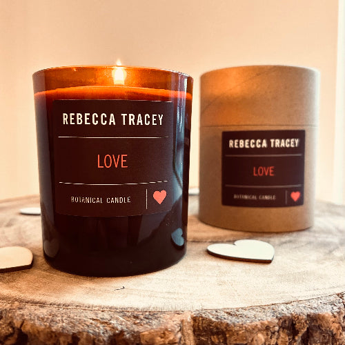 Rebecca Tracey 'Love' candle on a wooden surface with packaging in the background.