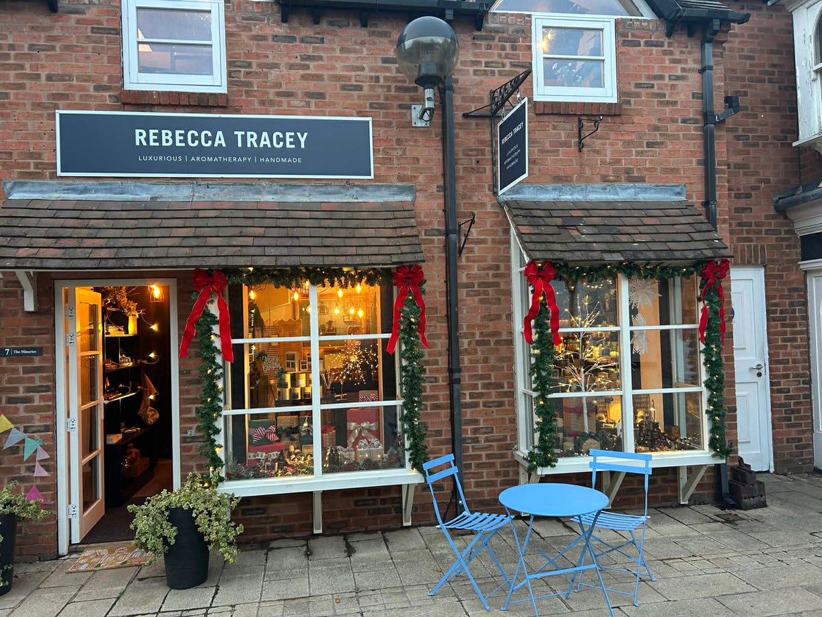 Brick building with 'Rebecca Tracey' sign, decorated windows, and outdoor seating area.