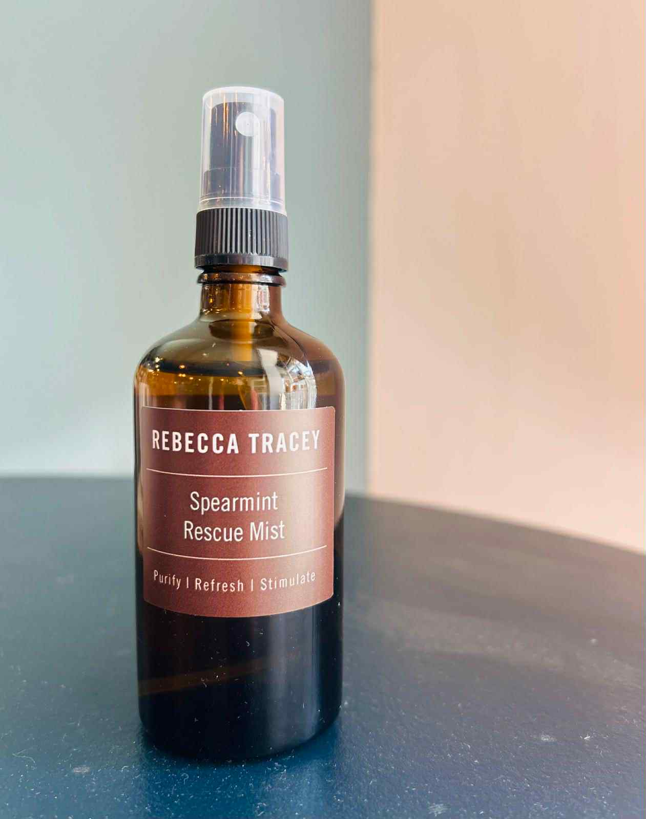 Bottle of Rebecca Tracey Spearmint Rescue Mist on a reflective surface with a neutral background